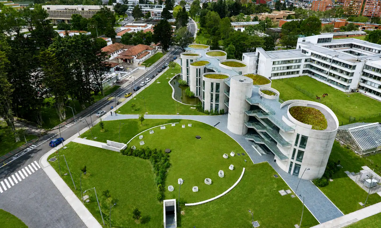 Edificio de torres cilíndricas con cubiertas vegetales rodeado de prados