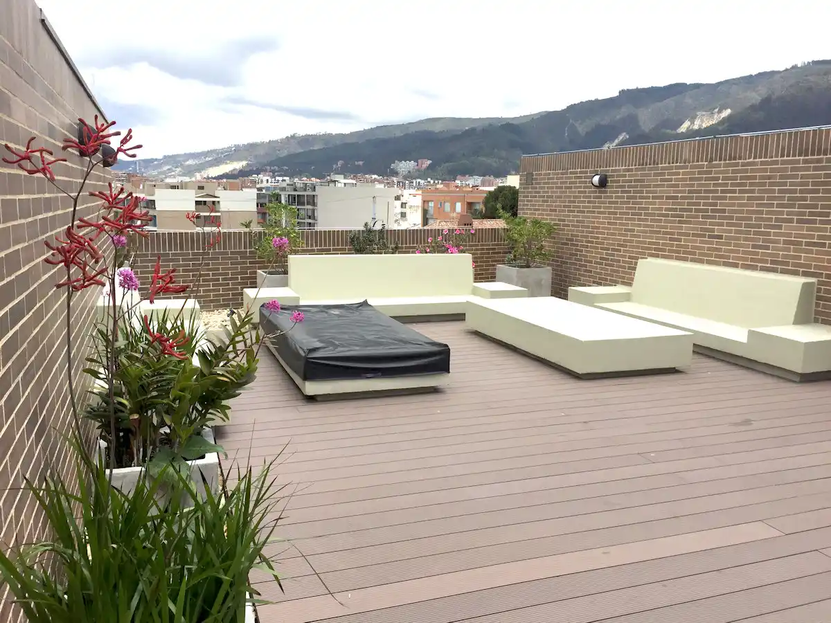 Terraza con bancas y camas de concreto, materas y vista a los cerros de Bogotá